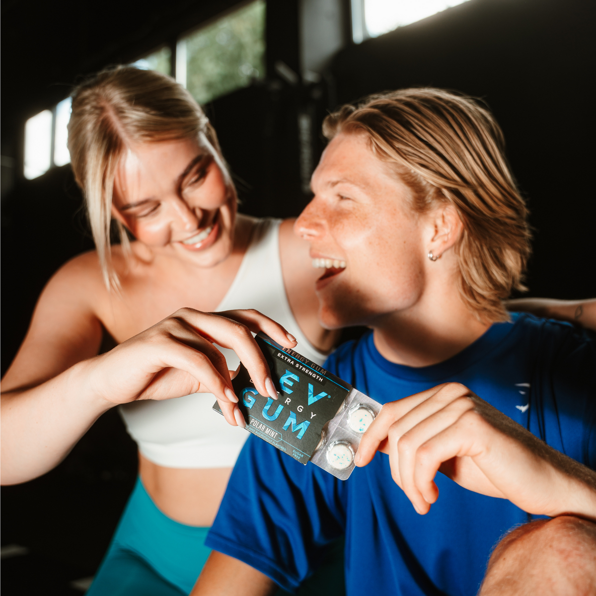 Two people holding a package of rev Gum in an indoor setting